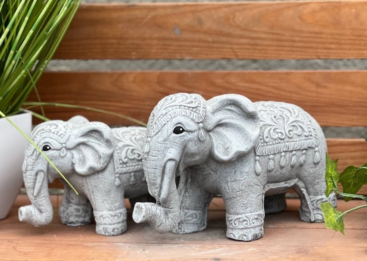 Zwei dekorative Elefantenfiguren aus Stein mit kunstvollen Mustern und Verzierungen auf einer Holzfläche.