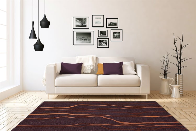 Moderner Wohnraum mit hellem Sofa, dunklem Teppich mit Wellenmuster, Bildergalerie und schwarzen Hängeleuchten auf Holzparkett.