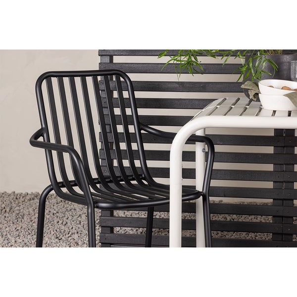 Schwarzer Metall Gartenstuhl mit Armlehnen neben weißem Tisch