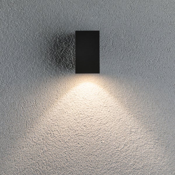 Moderne Wandleuchte in rechteckiger Form mit indirektem Lichtkegel nach oben an einer strukturierten Wand