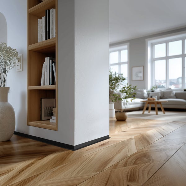 Heller Wohnraum mit Fischgrätparkett Bodenbelag, integriertem Wandregal aus Holz und Blick in ein offenes Wohnzimmer mit gemütlicher Einrichtung.