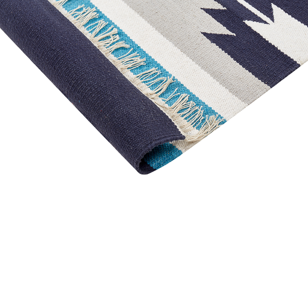Flachgewebter Teppich mit geometrischem Muster und Fransen an der Kante, Detailansicht der Textur und Rückseite.