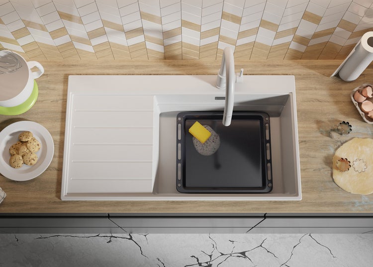 Draufsicht auf eine Küche mit Spüle, in der ein Backblech mit einem Schwamm gereinigt wird