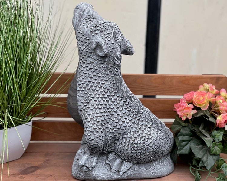 Steinguss-Gartenfigur in Form eines schuppigen Fabelwesens, das nach oben blickt, platziert im Gartenbereich.