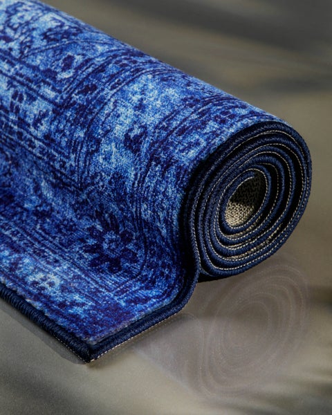 Eingerollter blauer Teppich mit orientalischem Muster in Vintage-Optik.