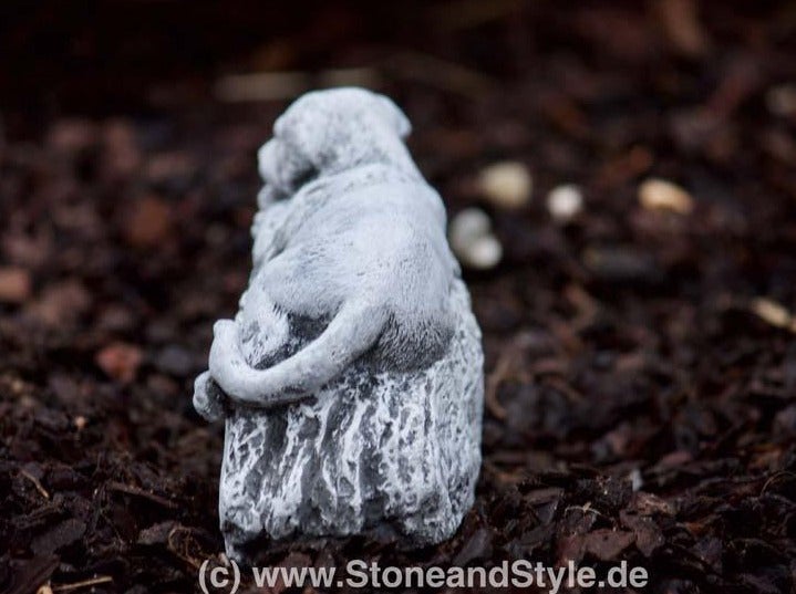 Gartenfigur Hund aus Steinguss sitzend auf einem Baumstumpf für die Außendekoration
