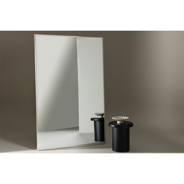 Stehender Spiegel neben zwei Beistelltischen mit dekorativen Schalen