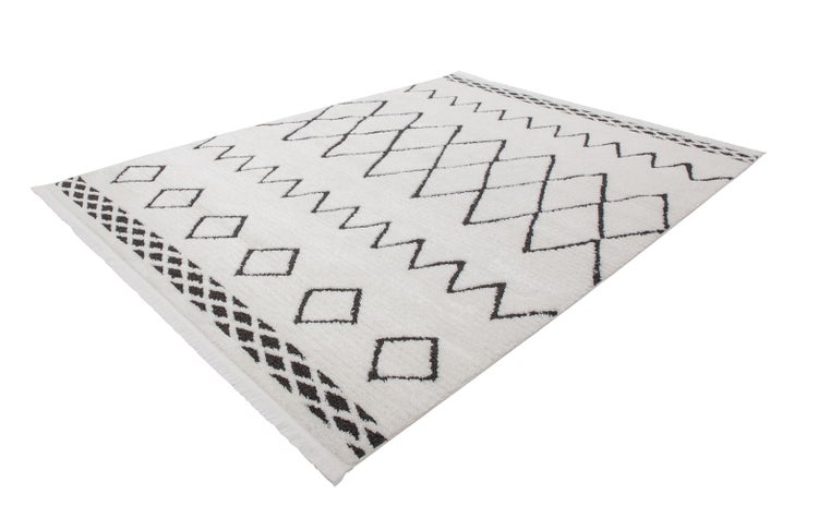 Rechteckiger weißer Teppich mit dunklem geometrischem Muster aus Rauten und Zickzacklinien sowie Fransen an den Enden.