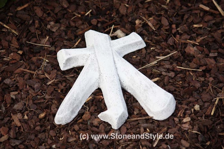Dekorative Gartenfigur aus Stein in Form eines Schriftzeichens liegend auf Rindenmulch.