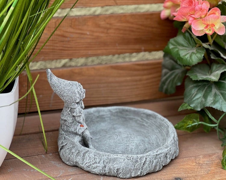 Dekorative Vogeltränke in Steinoptik mit einer kleinen, sitzenden Zwergfigur, geeignet als Gartendekoration.