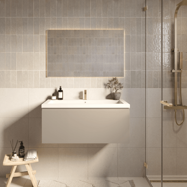 Modernes Badezimmer mit wandhängendem Waschtischunterschrank, weißem Waschbecken, beleuchtetem Spiegel und goldfarbenen Armaturen.