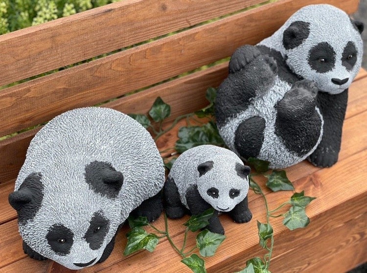 Drei Panda Gartenfiguren aus Stein auf einer Holzbank mit Efeudekoration