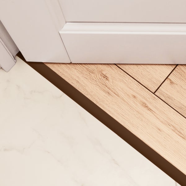 Detailansicht von weißen Sockelleisten, Bodenprofil und Bodenbelägen aus Laminat und Stein