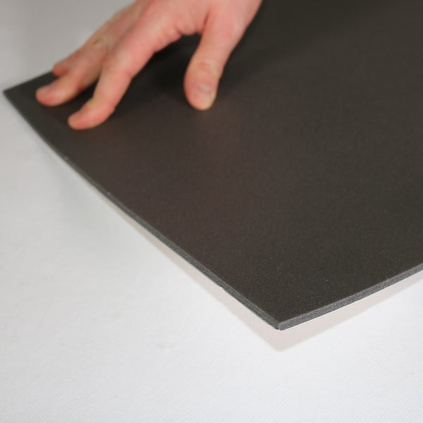 Eine Hand berührt eine flache, dunkle Platte aus Hartschaum oder Dämmmaterial.