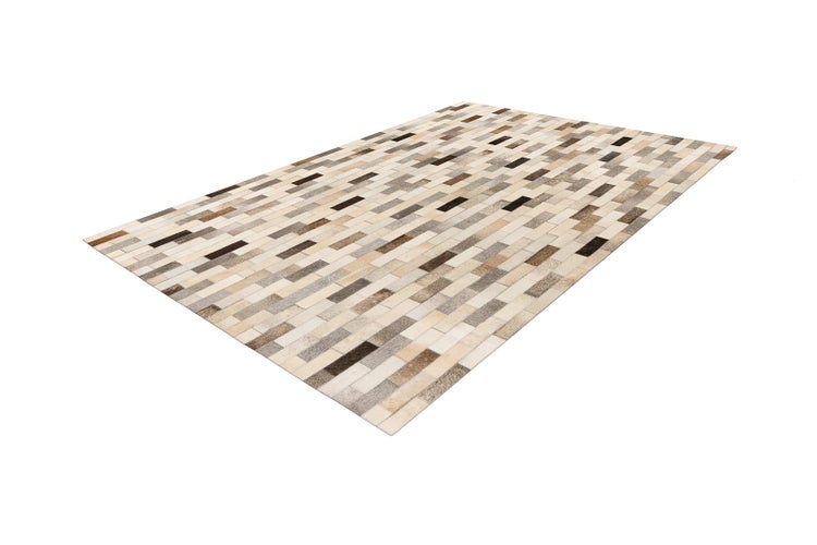 Patchwork-Teppich aus Kuhfell mit rechteckigem Muster in Naturtönen.