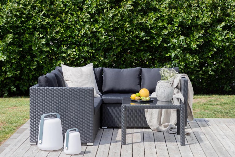 Gartenlounge-Set mit Tisch, Kissen und Dekoration auf einer Holzterrasse
