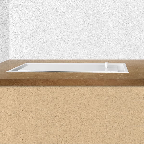 Flächenbündig eingebautes Kochfeld mit Abdeckung in einer Küchenarbeitsplatte vor einer strukturierten Wand.