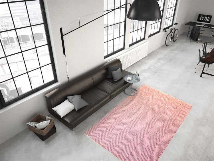 Moderner Teppich mit rosa Zickzack-Muster in einem hellen Wohnzimmer im Loft-Stil mit Ledersofa und Betonboden.
