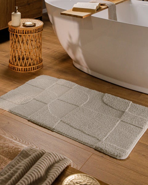 Beige Badematte mit geometrischem Reliefmuster und abgerundeten Ecken.