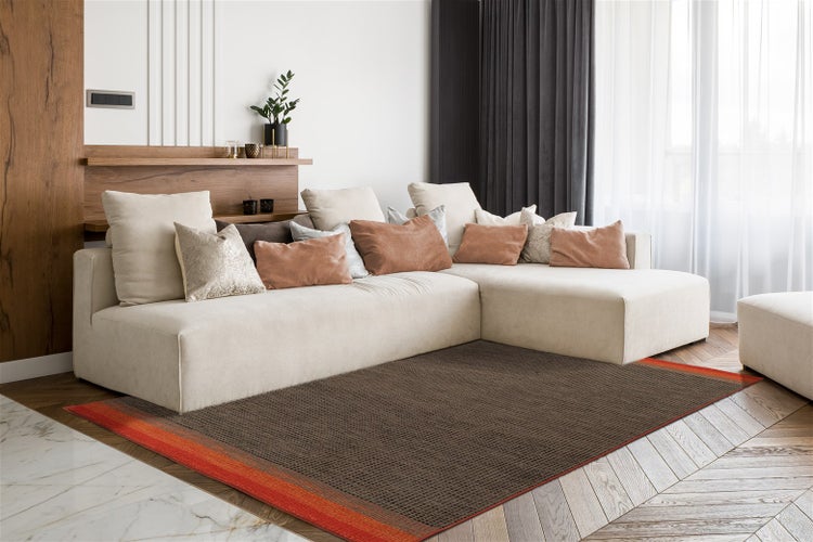 Moderner Wohnraum mit hellem Ecksofa auf Fischgrätparkett und einem strukturierten braunen Teppich mit orangefarbenem Rand.