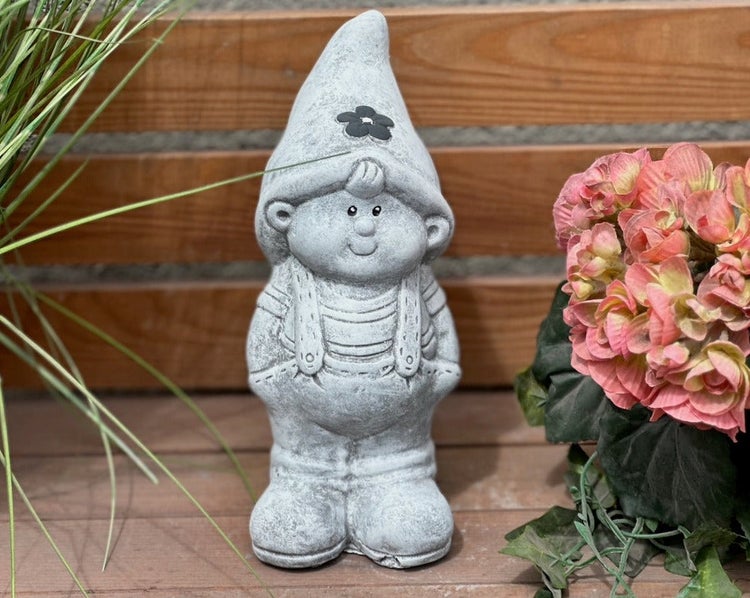 Gartenzwerg aus Stein in Form eines Jungen mit spitzem Hut und Latzhose.