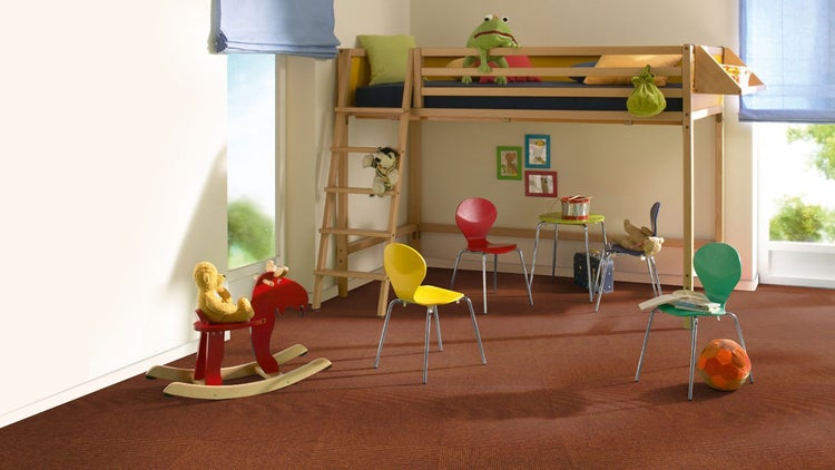 Hell gestaltetes Kinderzimmer mit braunem Teppichboden, einem Hochbett aus Holz, bunten Stühlen und einem Schaukelpferd.