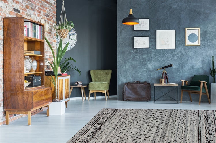 Modernes Wohnzimmer mit Holzregal, grünen Samtsesseln, großem Teppich, Ziegelwand und strukturierter blauer Wand.