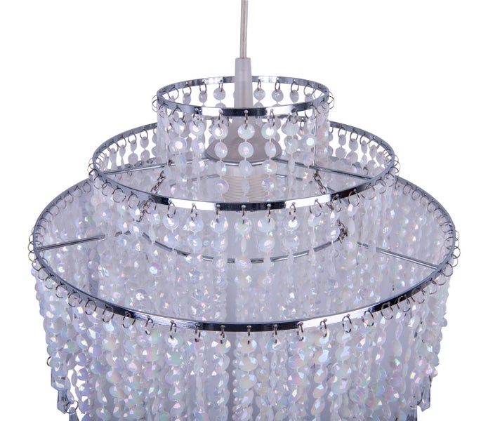 Szene mit einem Kronleuchter mit Perlen, einem runden Tisch mit Obst und einer Flasche Wein.