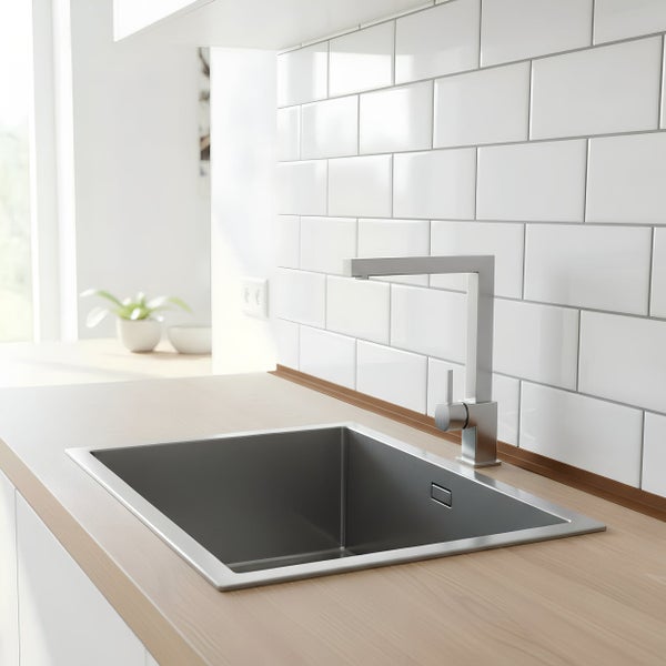Moderne Küchenspüle aus Edelstahl mit Einhebelmischbatterie in einer hellen Küche mit Fliesenrückwand.