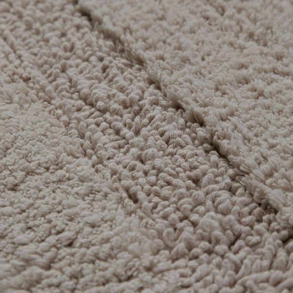 Nahaufnahme eines Badeteppichs mit Schlingenstruktur und Streifenmuster.