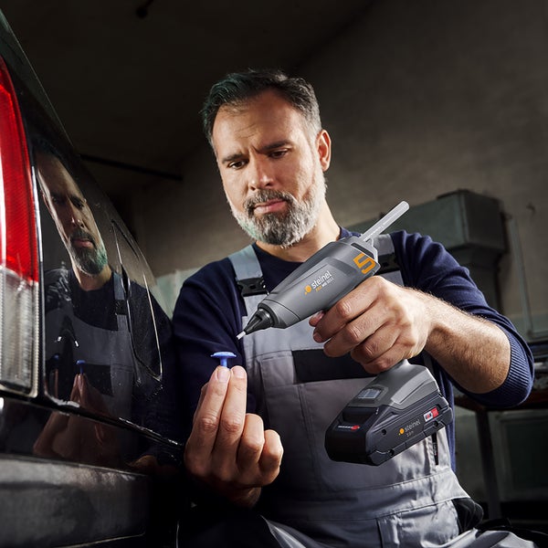 Handwerker verwendet die Akku-Heißklebepistole Steinel MG 5011 zur Reparatur an einem Auto.