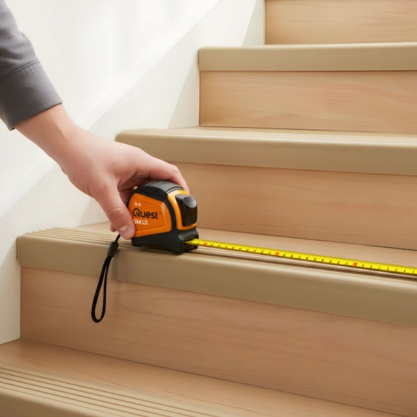 Eine Person misst mit einem Rollbandmaß eine Treppenstufe.