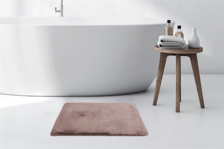 Flauschiger, rechteckiger Badteppich in einem hellen, modernen Badezimmer mit freistehender Badewanne und einem Holzhocker.