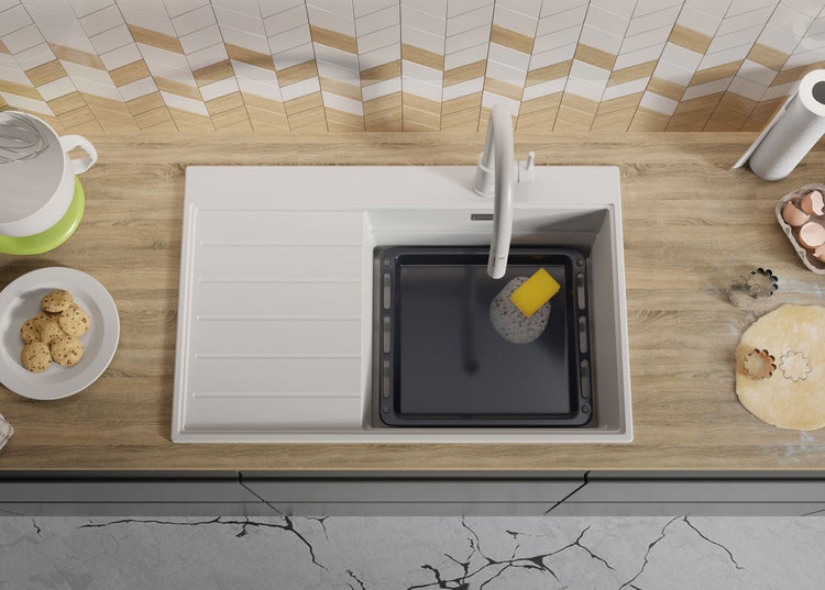 Küchenspüle mit Spülbecken, Backblech, Spülmittel und Küchenutensilien auf einer Arbeitsplatte.