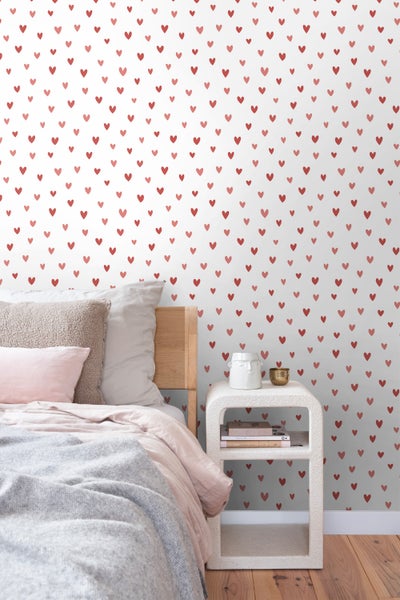 Schlafzimmer mit Herzchentapete, Bett und Nachttisch