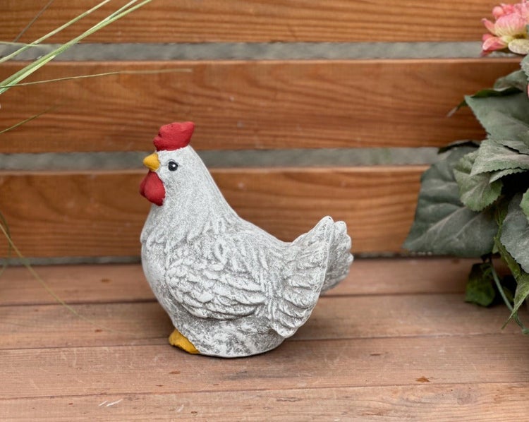 Dekoratives Deko-Huhn für den Garten in grauer Steinoptik mit rotem Kamm auf einer Holzoberfläche.