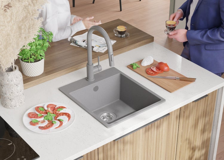 Küchenszene mit Spüle, Armatur und zubereiteten Speisen auf der Arbeitsfläche.