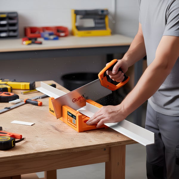 Eine Person sägt mit einer Handsäge ein Werkstück in einer Gehrungslade auf einer Werkbank.