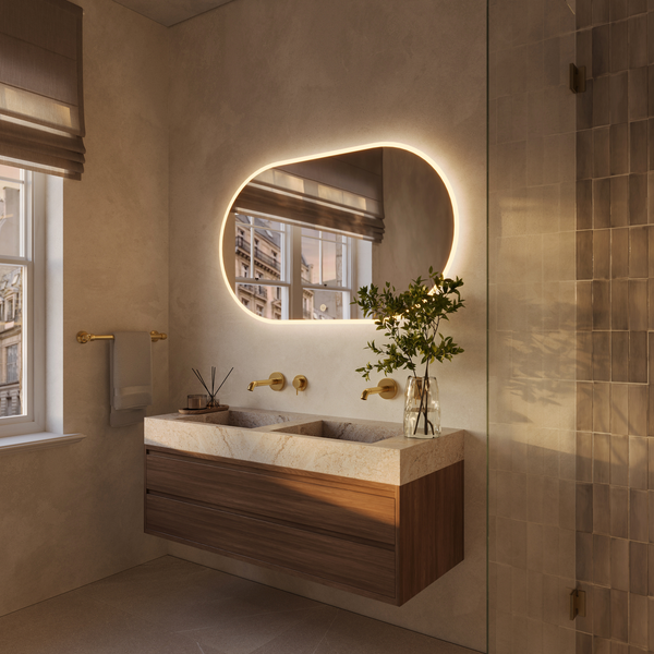 Modernes Badezimmer mit Waschtisch aus Stein, Holzunterschrank und beleuchtetem Wandspiegel in organischer Form.