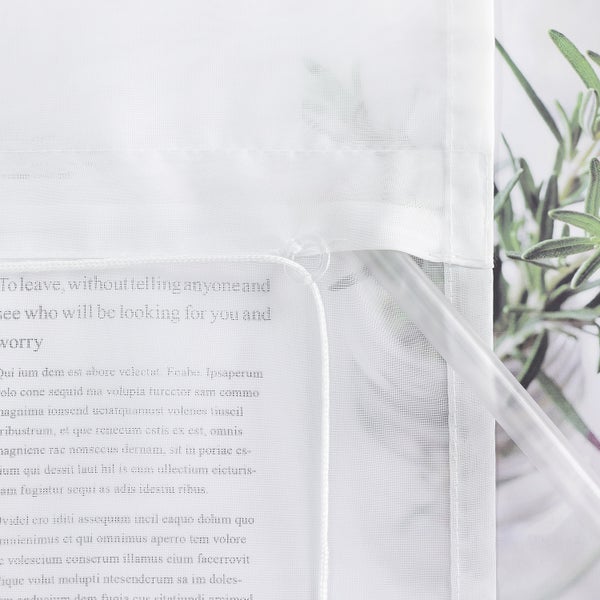 Detail einer weißen, transparenten Gardine mit Textdruck