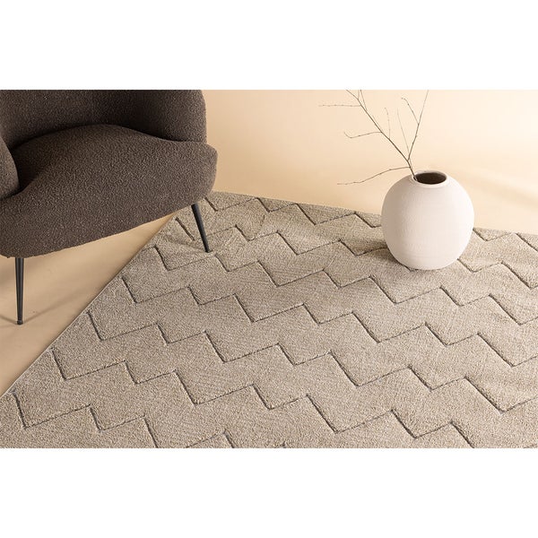 Teppich mit Zickzackmuster, Sessel und Vase mit Zweigen für eine Raumdekoration