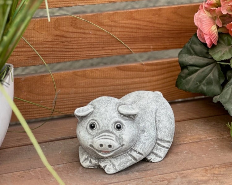 Dekorative Gartenfigur in Form eines liegenden Schweins in Steinoptik.