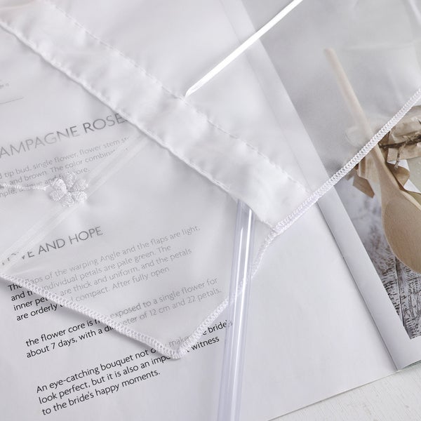 Detailaufnahme eines weißen Stoffes mit Stickerei auf einer Zeitschrift