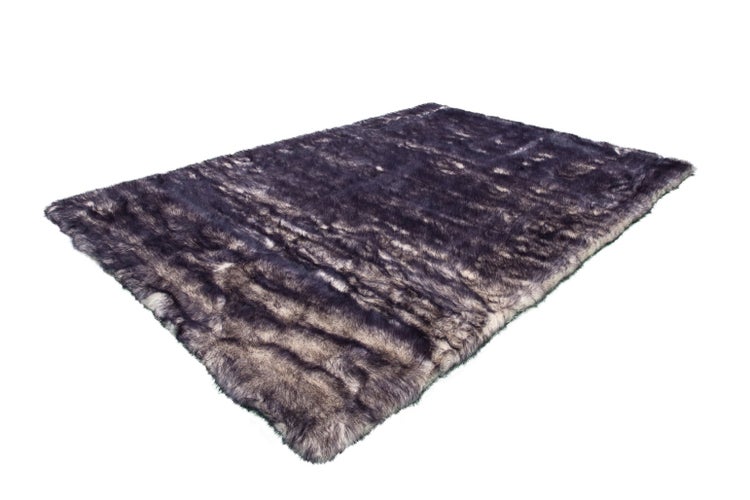 Rechteckiger Kunstfellteppich aus Langflor in meliertem Violett und Grau.
