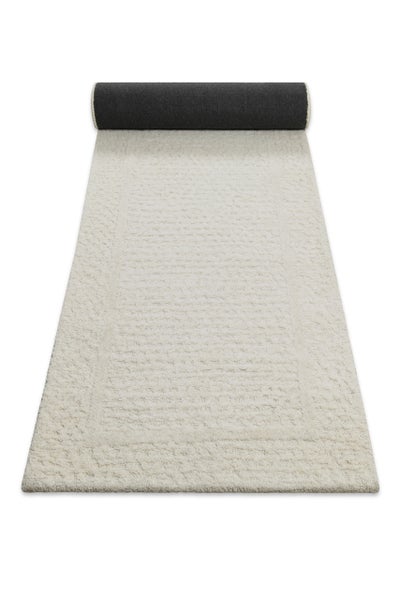 Beige strukturierter Teppichläufer mit weichem Flor, teilweise ausgerollt.