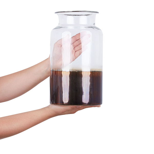 Hände halten eine große Blumenvase aus Glas