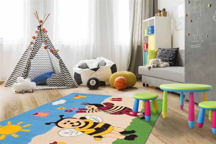 Helles Kinderzimmer mit buntem Spielteppich mit Bienenmotiv, Spielzelt, grauem Sofa und farbenfrohen Kindermöbeln.