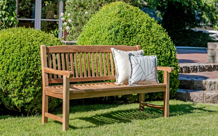 Gartenbank aus Holz mit Kissen auf Rasen