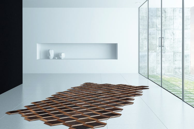 Geometrischer Teppich aus Leder-Patches in einem minimalistischen, hellen Raum mit großer Fensterfront und weißer Wandnische.
