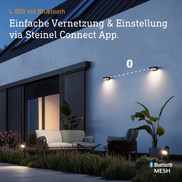 Zwei Steinel L 800 Außenwandleuchten mit Bluetooth Mesh Technologie an einer modernen Hausfassade mit Terrasse bei Dämmerung.